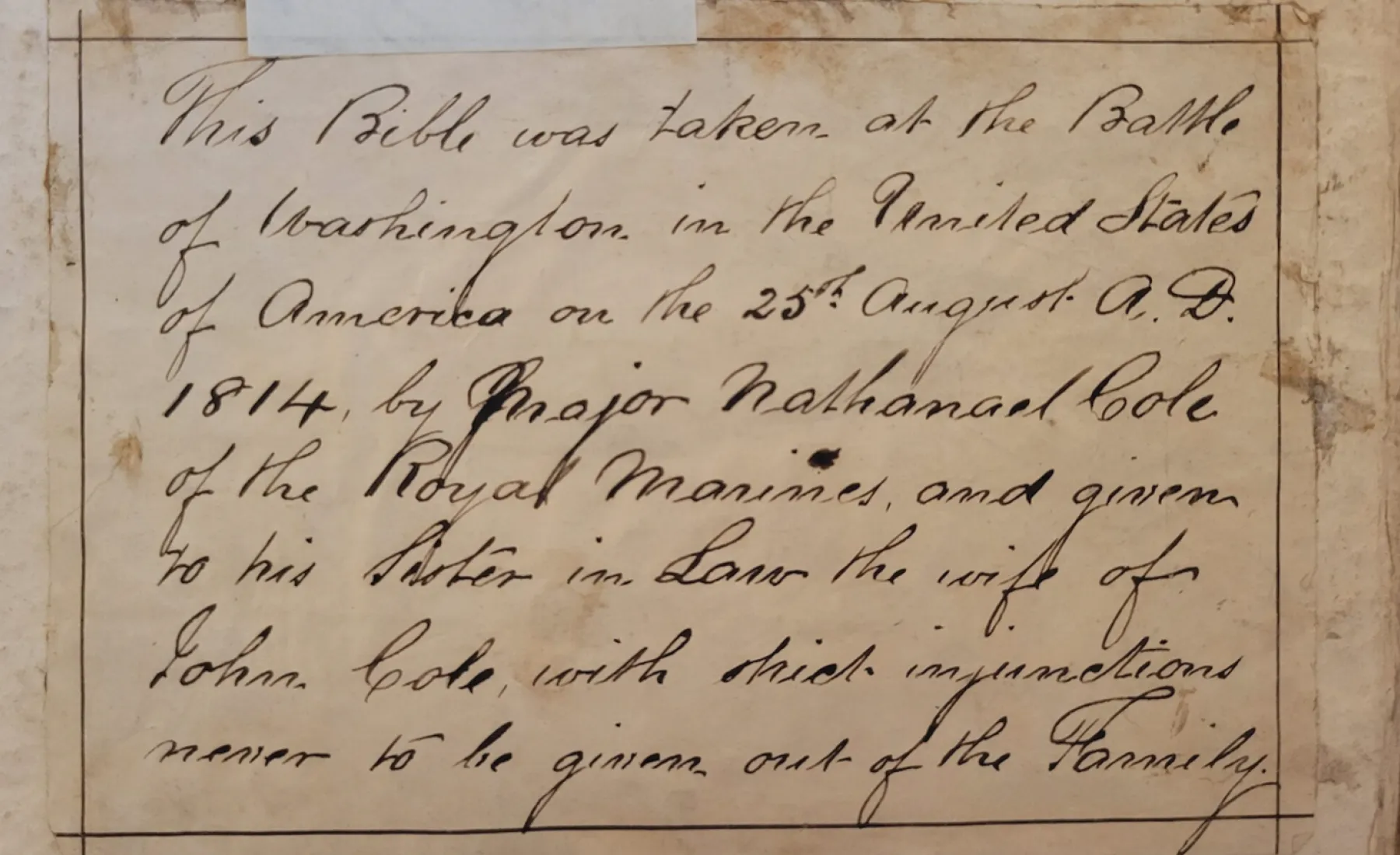 A handwritten note in cursive text describing that the Bible was taken during the Battle of Washington on August 25, 1814, by Major Nathanael Cole of the Royal Marines, given to his sister-in-law, with instructions to keep it within the family.